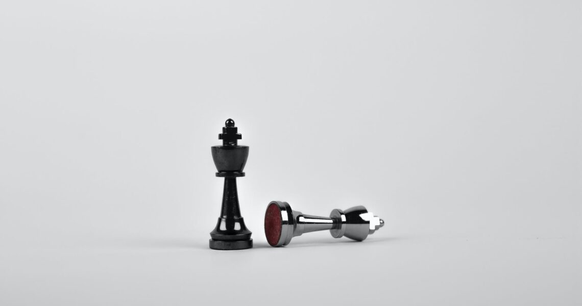 two silver chess pieces on white surface